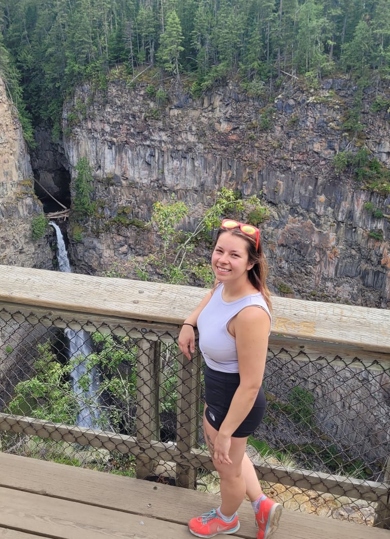 A smiling woman wearing pink sunglasses and a purple shirt