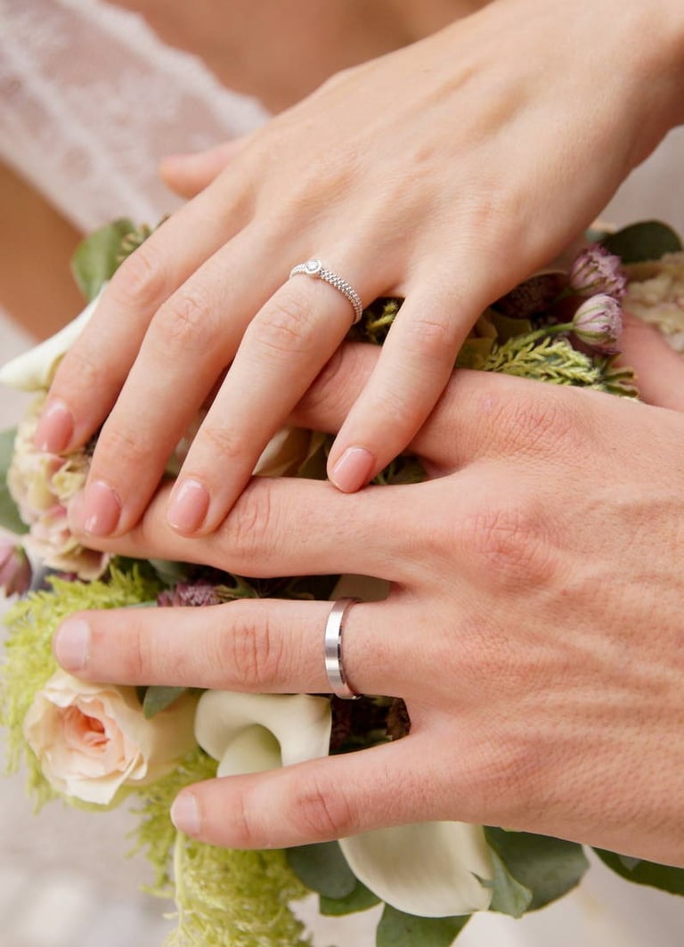 photo of newly wed hands on the bouquet with the wedding bands