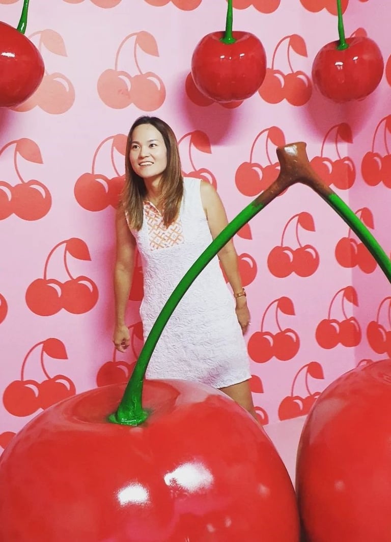 an asian woman standing in front of a wall with cherries