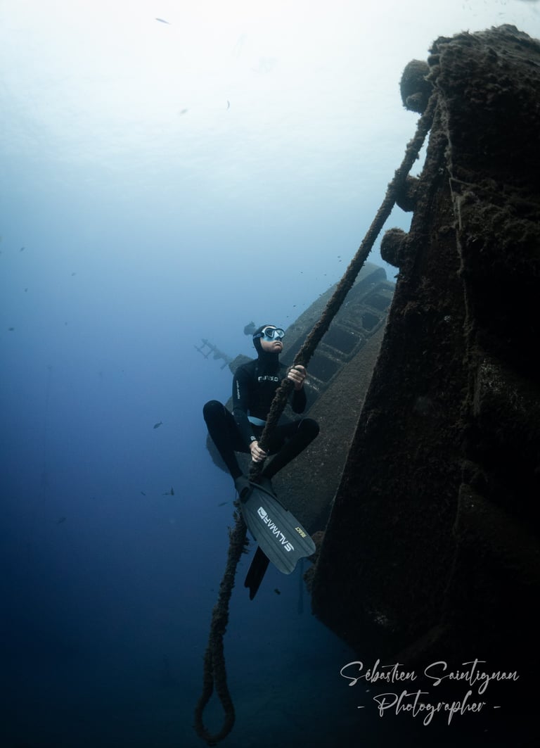 a freediver is holding a rope for an underwater photoshoot. Photo taken by Sébastien Saintignan