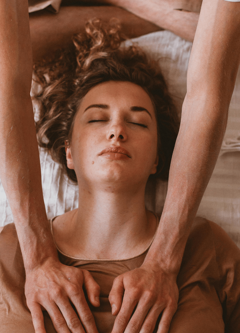 Practitioner performing gentle energy work on a woman’s chest and shoulders as she relaxes