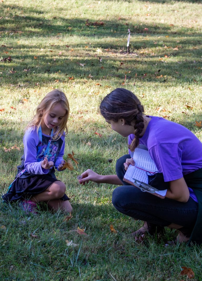 Teacher with one of our youth students outside, picking up natural pieces for an art project.