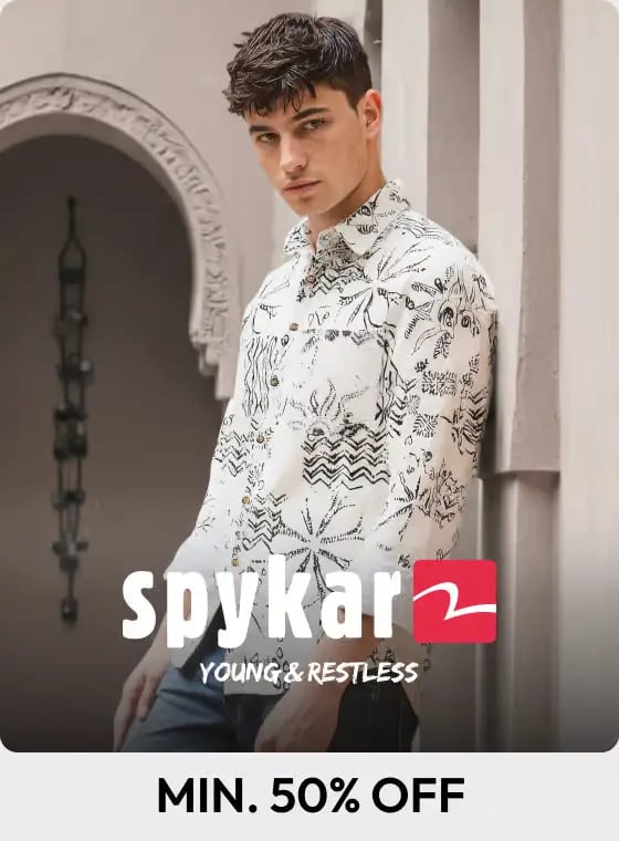 A male model wearing a Spykar patterned white button-down shirt with a black graphic print.