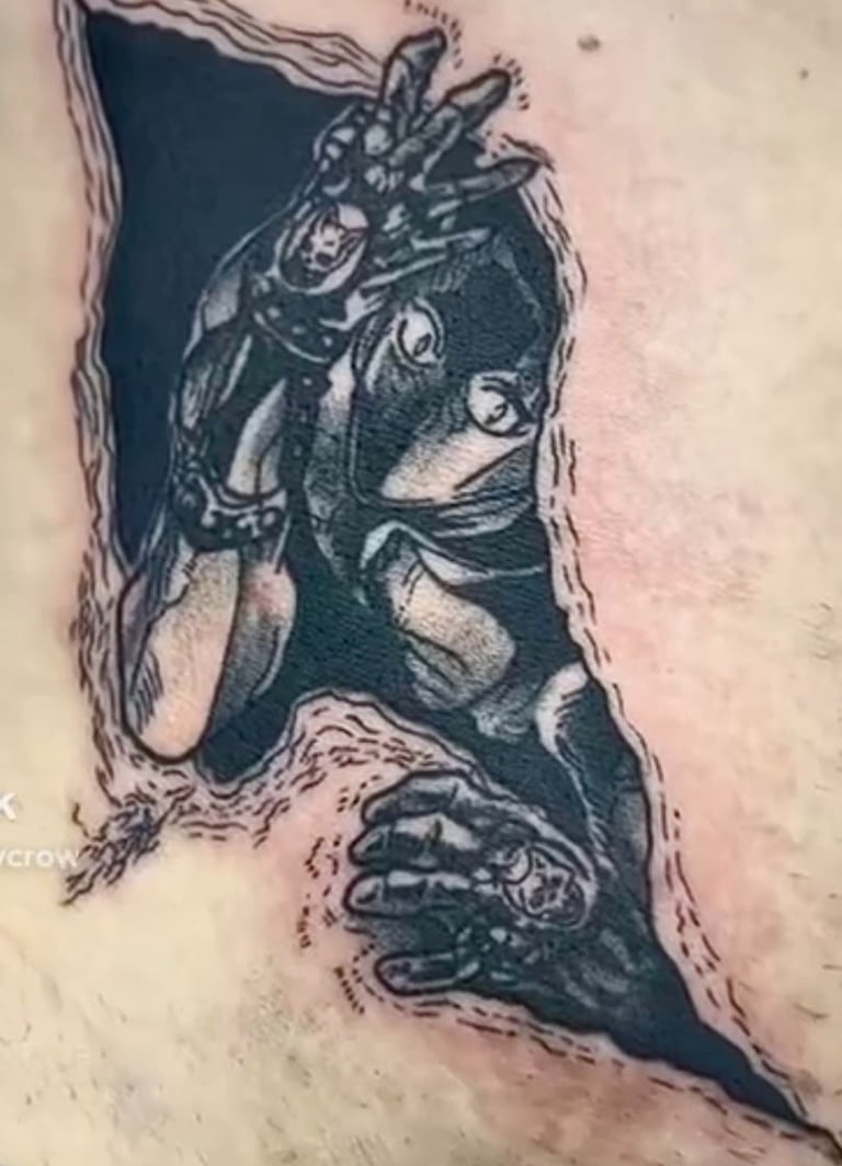 Detailed black and grey anime tattoo of Killer Queen from JoJo's Bizarre Adventure emerging through skin.