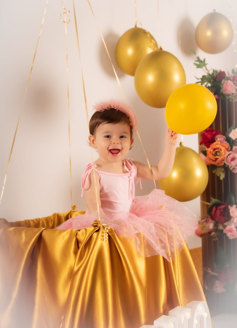 a little girl in a pink dress and a gold balloon