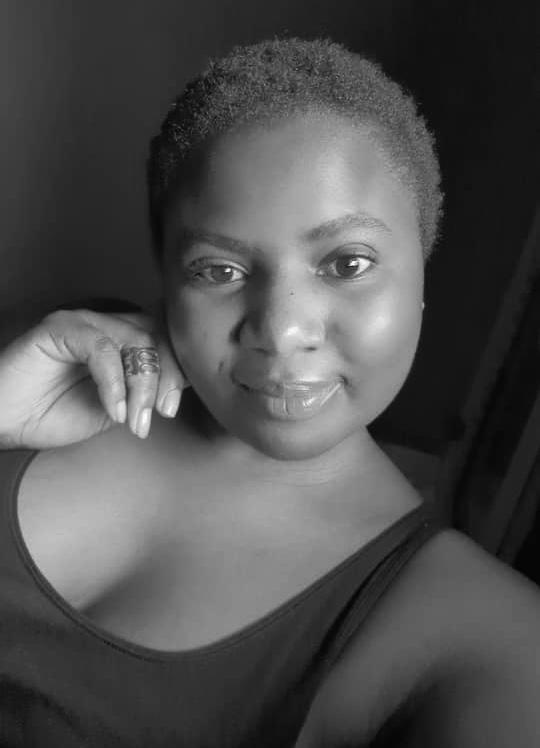 a woman with a hand on her jaw smiling at he camera