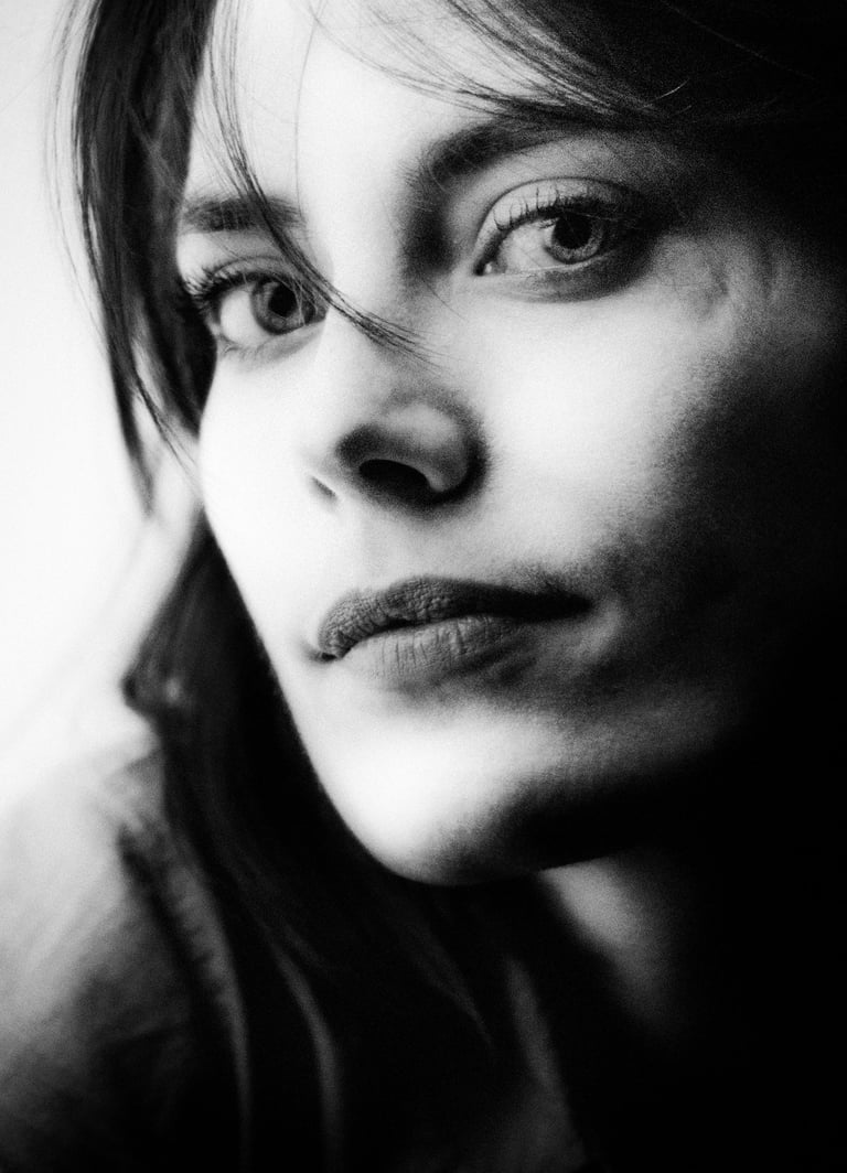 Close-up black and white portrait of a young woman with a thoughtful expression.