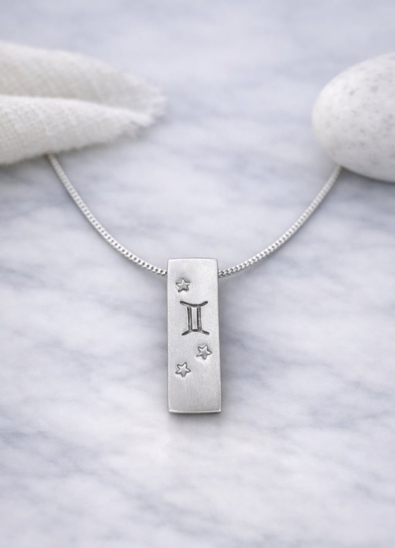 Handmade 999 silver Gemini zodiac necklace with a vertical bar pendant on a marble surface.