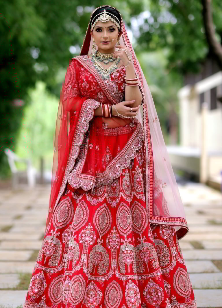Traditional Indian bride in red lehenga with heavy jewelry, maang tikka, and flawless bridal makeup.