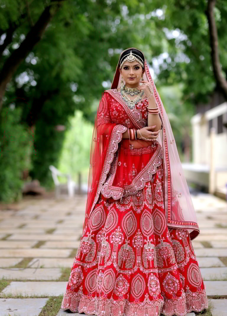 Traditional Indian bride in red lehenga with heavy jewelry, maang tikka, and flawless bridal makeup.