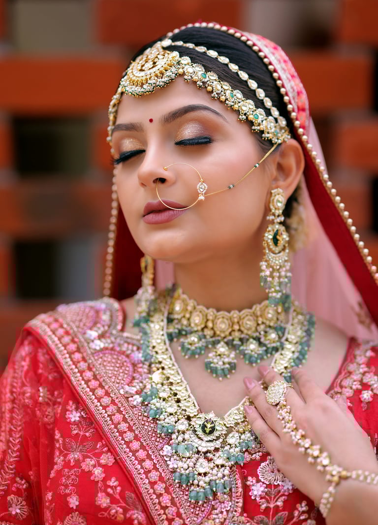 Traditional Indian bride in red lehenga with heavy jewelry, maang tikka, and flawless bridal makeup.