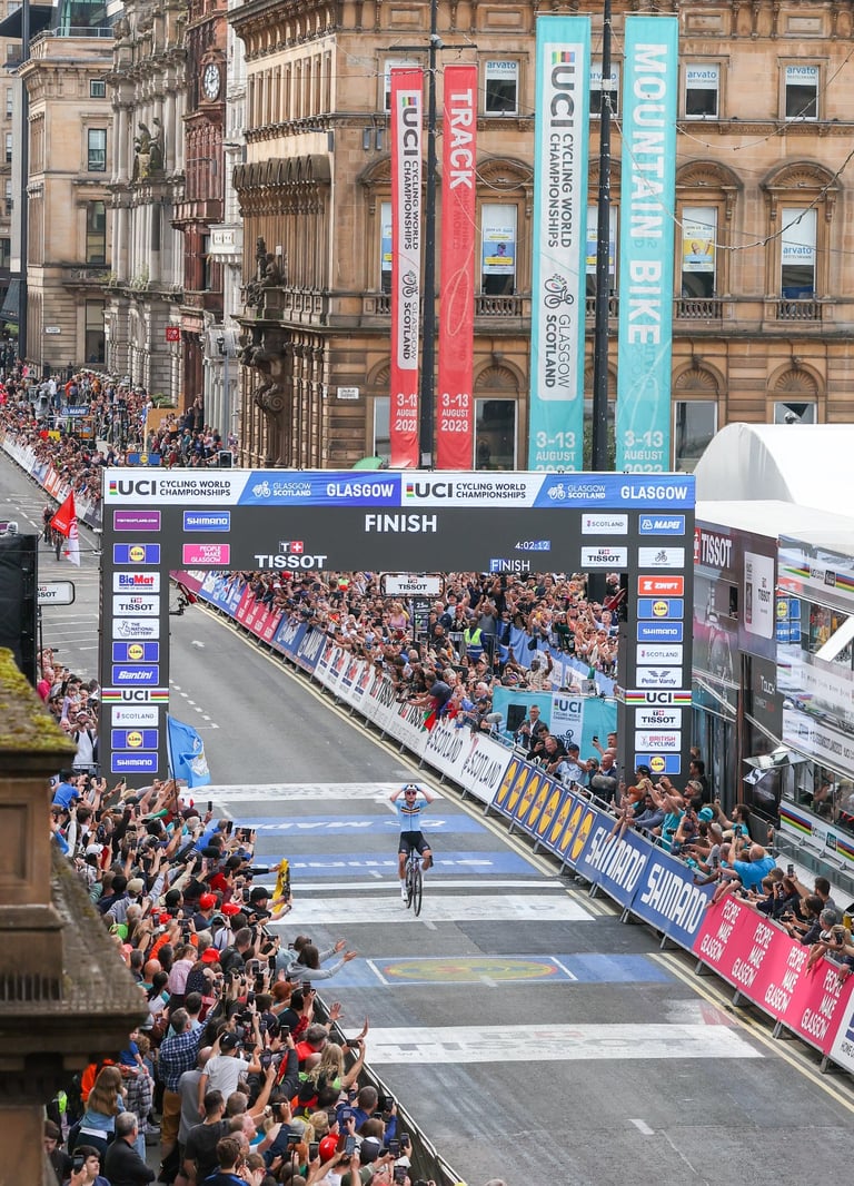 A professional bike riders winning a race whilst thousand of people watch and support