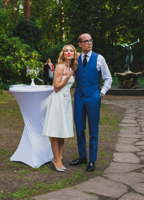Bride and groom posing with photo booth accessories.