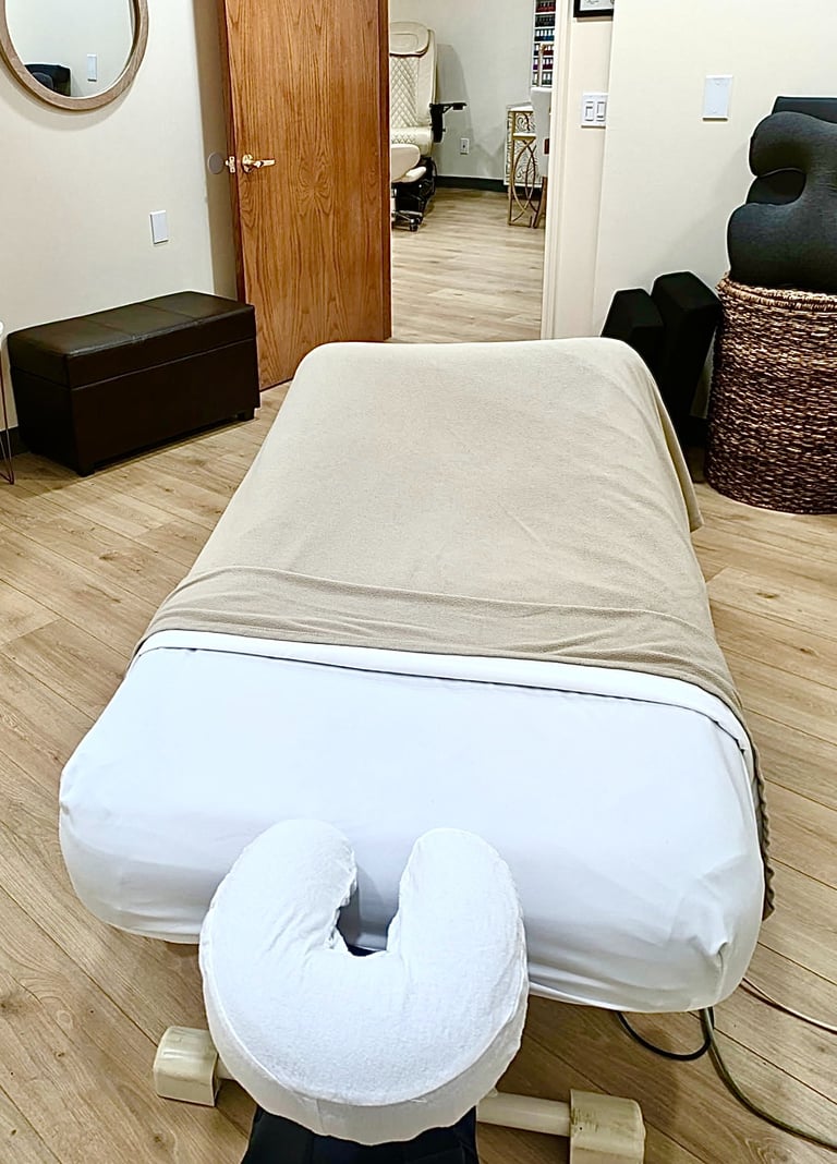Professional massage therapy table with white linens and a face cradle in a spa treatment room.