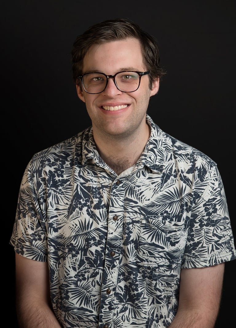 a man in a blue shirt and glasses with big smile