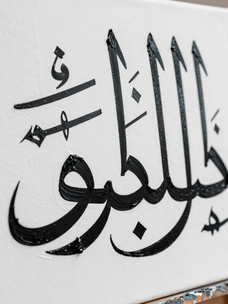 A close-up photograph of a contemporary art canvas in a high-end Middle Eastern studio. Sharp detail of black oil paint texture forming elegant Arabic calligraphy strokes against a stark white background. Natural, bright lighting.