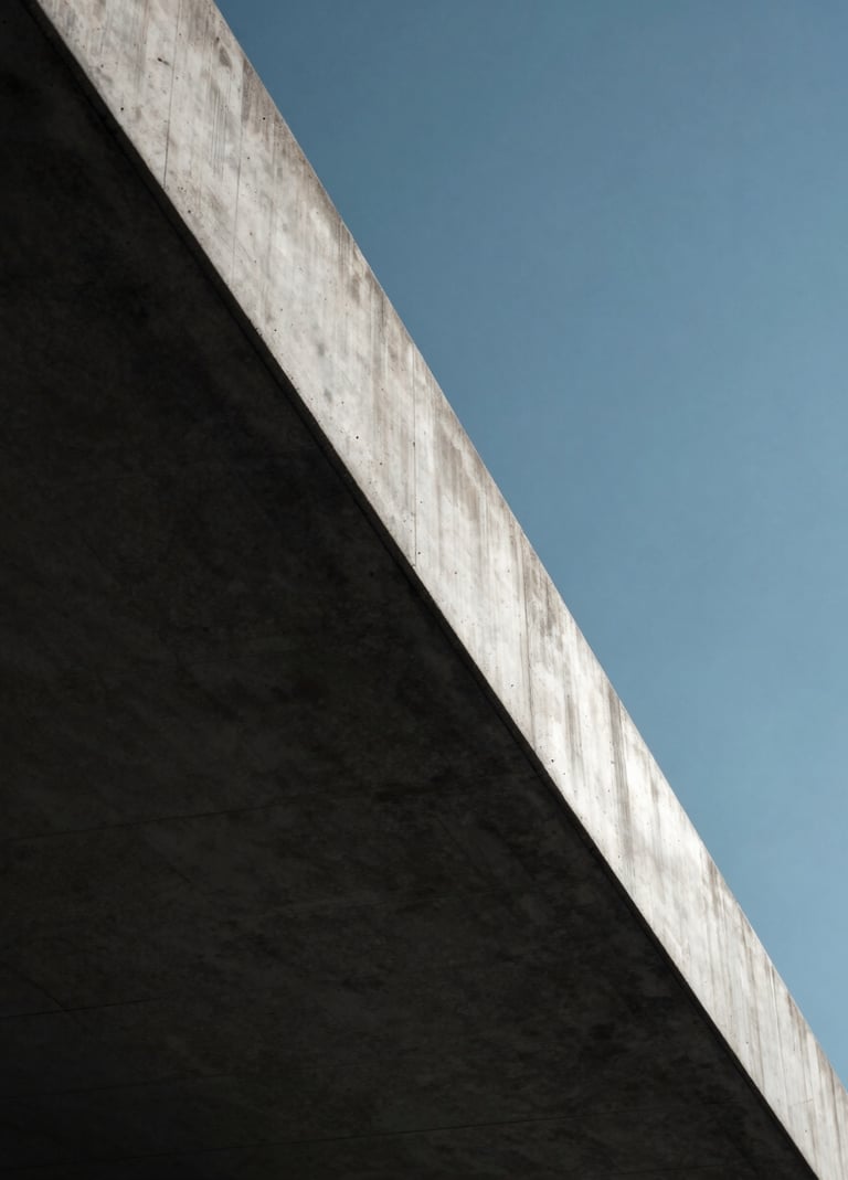 A close-up photograph of a concrete edge meeting a clear sky. The lighting is harsh midday sun creating a sharp division between Midnight Black shadow and Ice White highlights. Sophisticated architectural detail.