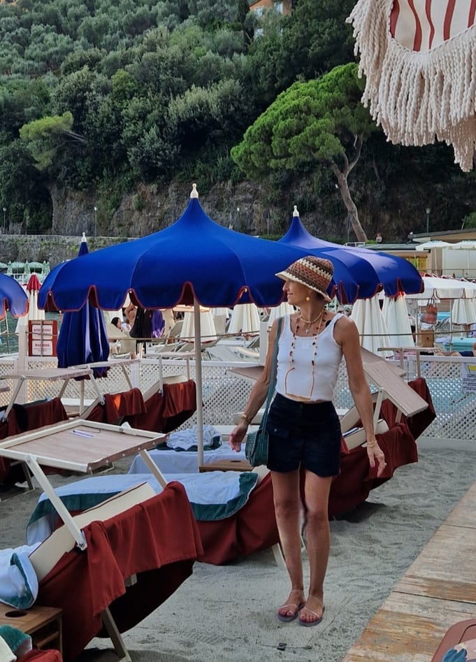 Mary Tornariti on sandy beach with blue umbrellas at Paraggi Bay near Portofino.
