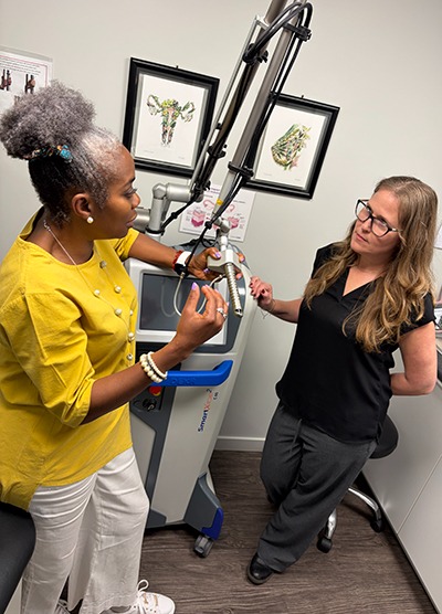 dr. aluko talking to female patient in front of monalisa touch equipment