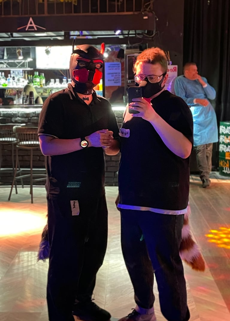 2 men in pup masks standing in a club.