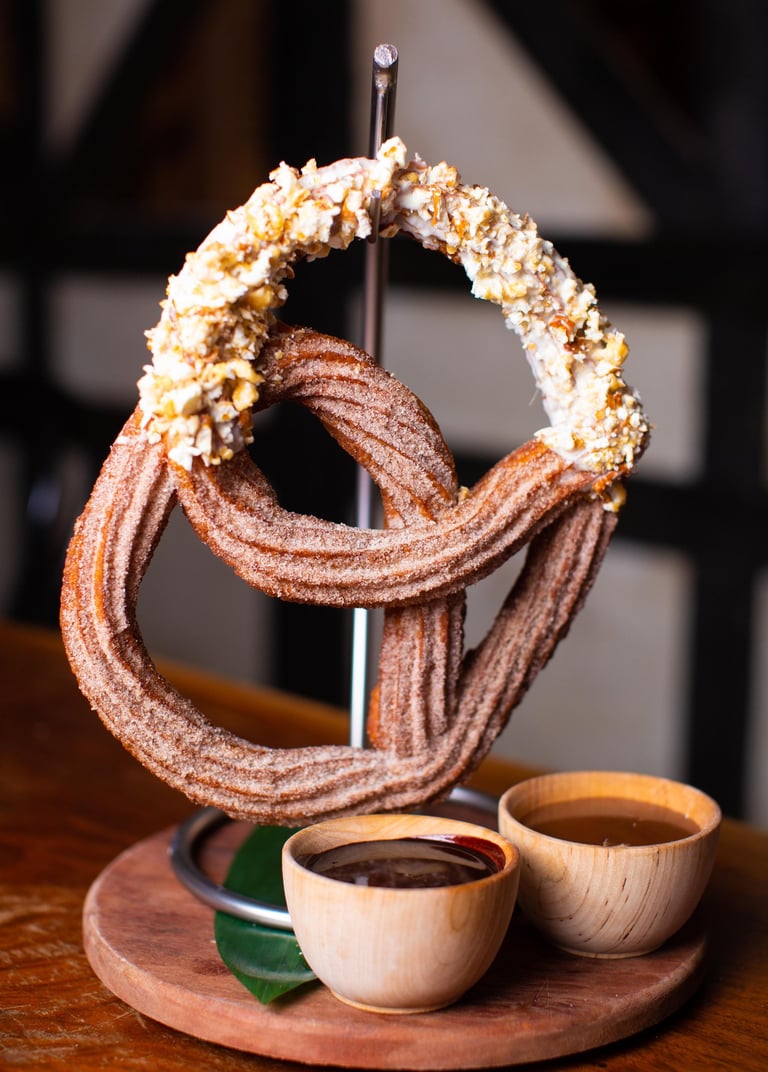 a huge churro pretzel hanging from a stand like a pretzel