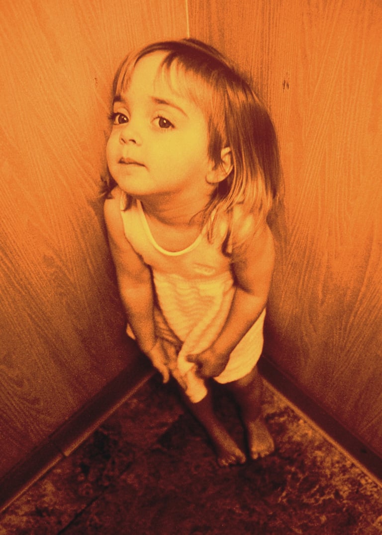 a little girl standing in a corner of a room