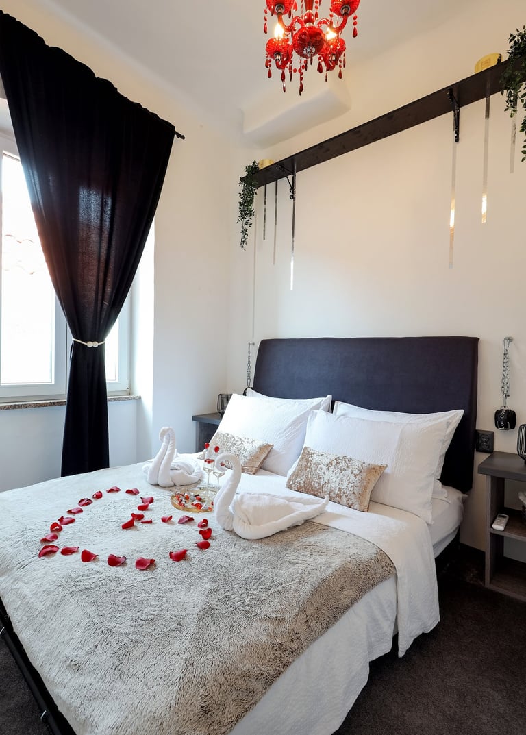 The photo shows honeymoon special setting of the bedroom in the BDSM Love Apartment. Champagne, rose petals, restraints.