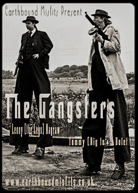 Performers on stilts dressed as 1920s gangsters with props for the Earthbound Misfits street theatre.