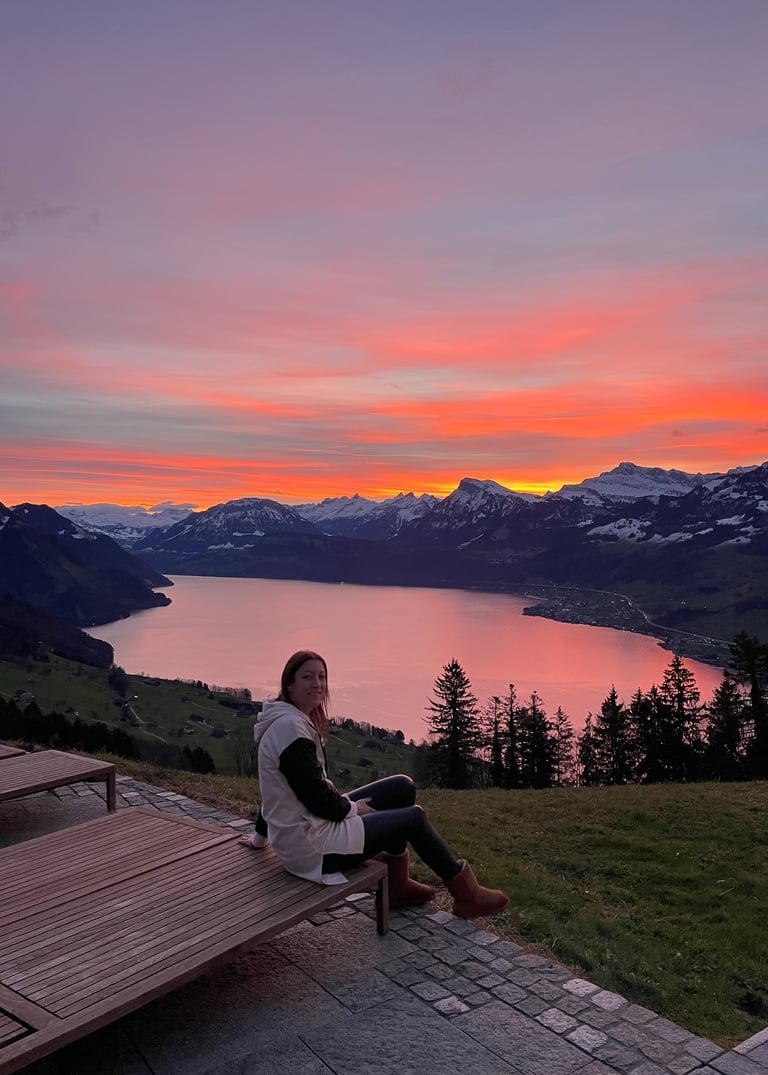 a woman sitting on a bench in front of a sunset