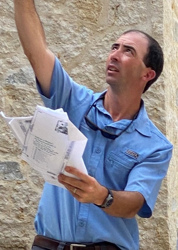 a man in a blue shirt is holding a cell phone designing lights on a house