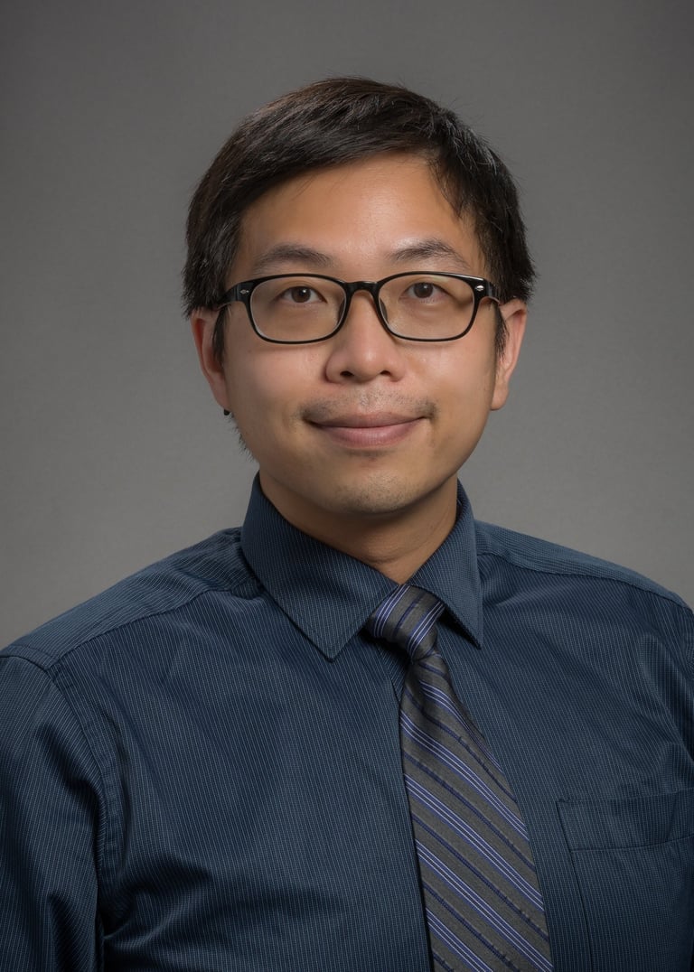a man in a blue shirt and tie dye on a gray background