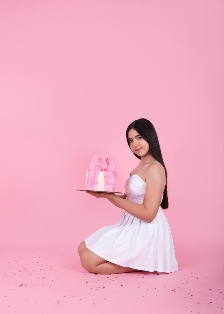 niña adolescente sentada en el piso con un pastel, en un set completamente rosa celebrando su cumple