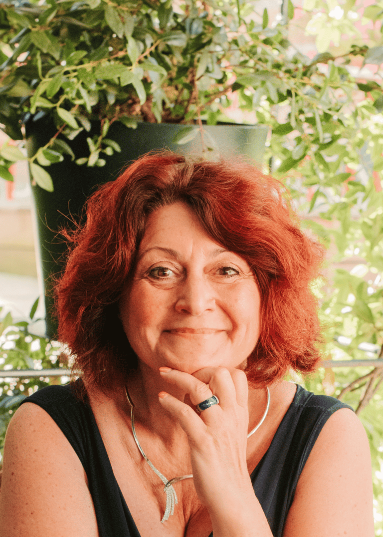 Flo Salort assise, main sous le menton, exprimant bienveillance, joie et leadership féminin