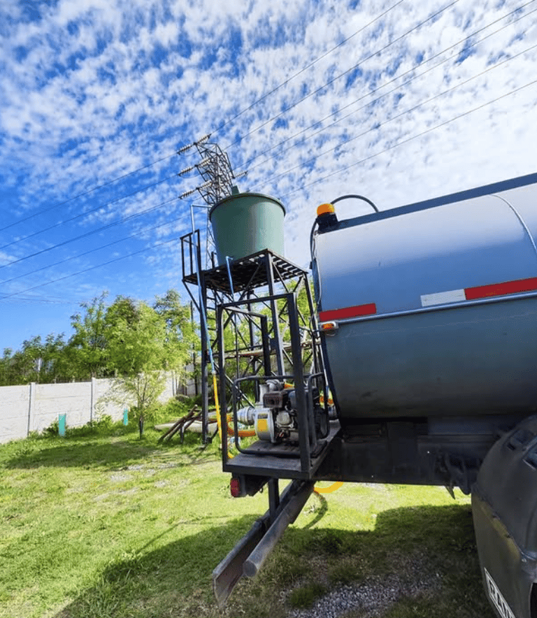 Camión aljibe llenando un estanque con agua potable