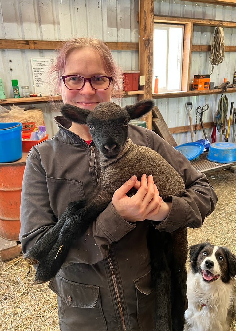 Rachael holding a lamb in her barn