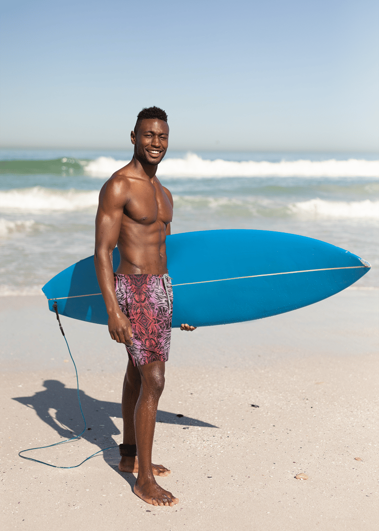 a man in a swimsuit holding a surfboard
