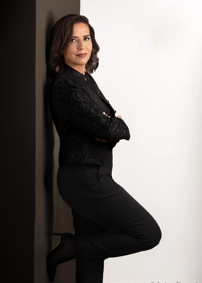 a corporate woman in a black shirt and black pants leaning against a wall