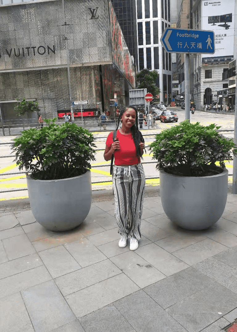 a woman standing on a sidewalk next to a large potted planter