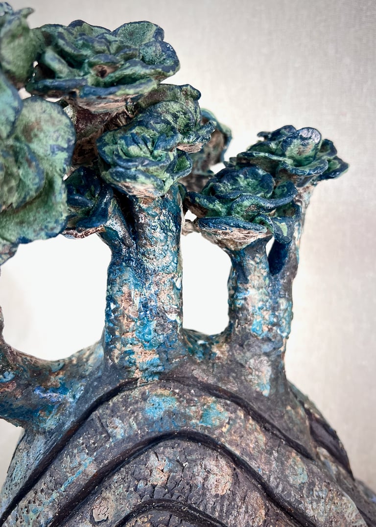 Abstract ceramic sculpture with blue and green glazes resembling textured trees and succulent flora.