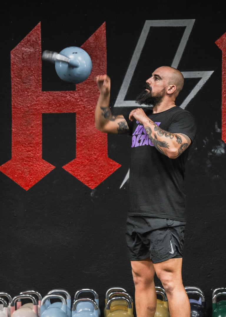 a man in a black shirt and shorts is holding a kettle kettlebell