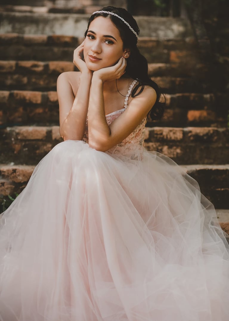mujer adolescente en un vestido rosa sentada en las escaleras celebrando sus XV años