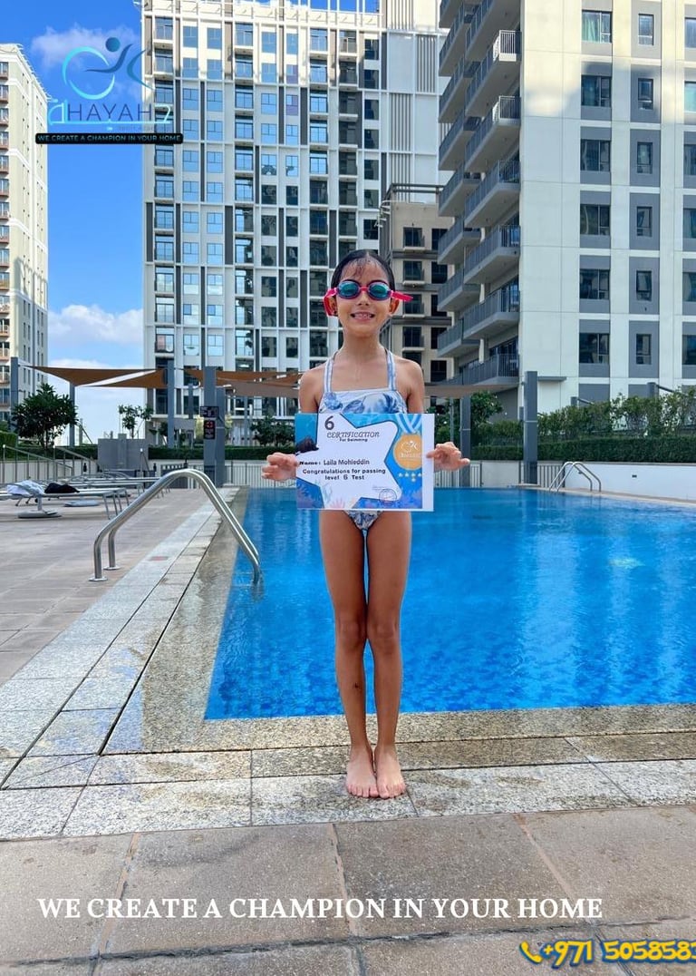 Young girl holding a swimming certificate by a luxury pool after finishing lessons at Hayah Swimming Academy.