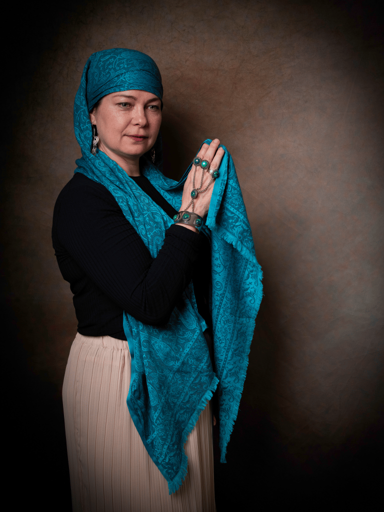 Portrait of a Kazakh woman wearing traditional scarf and jewellery.