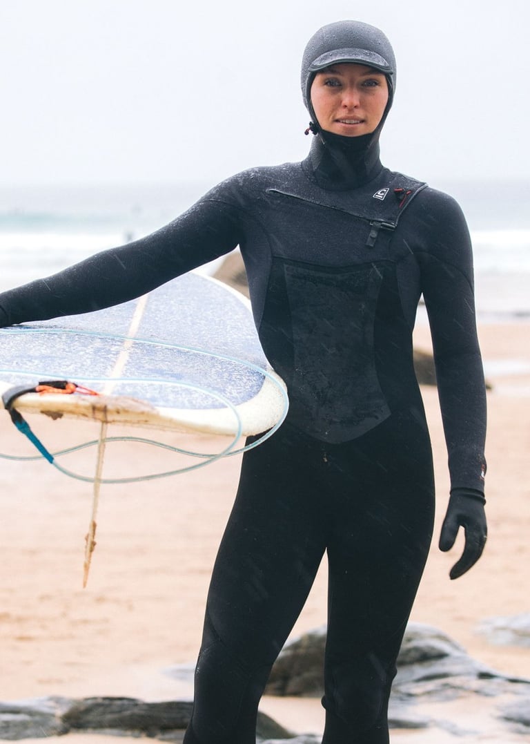 A female surfer wearing full winter wetsuit equipment