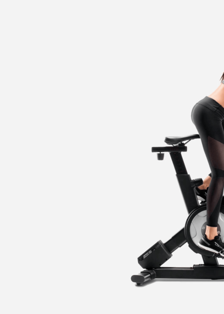 a woman in a black top and leggings on a stationary bike