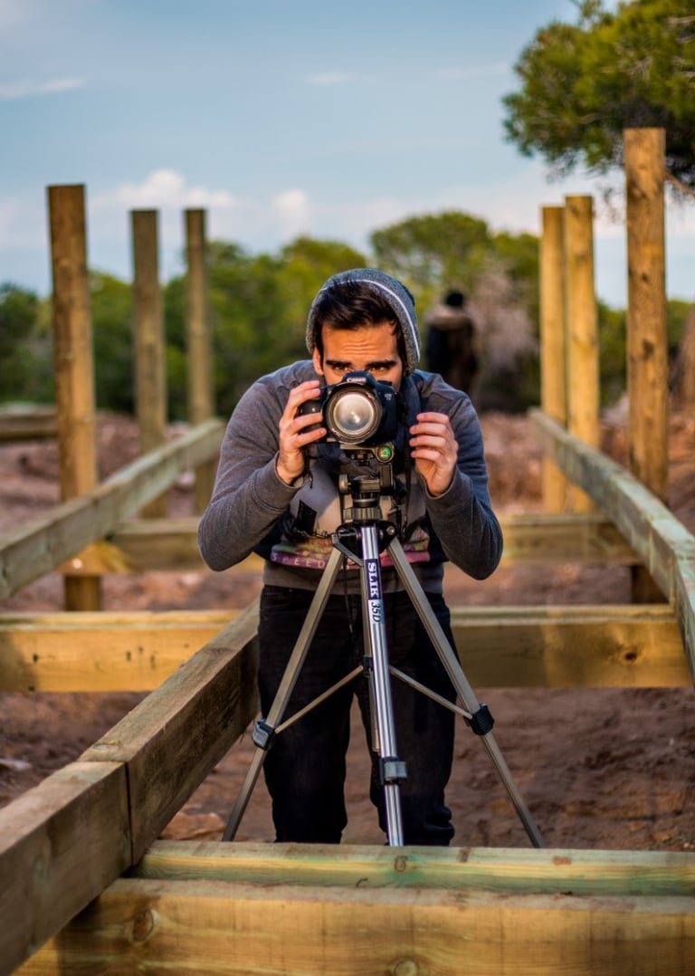 un hombre tomando una fotografía en un antiguo puente de madera