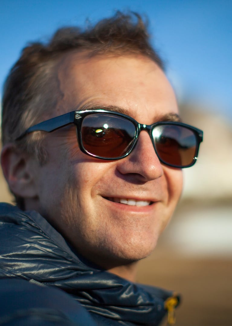 a man in sunglasses and a jacket is smiling