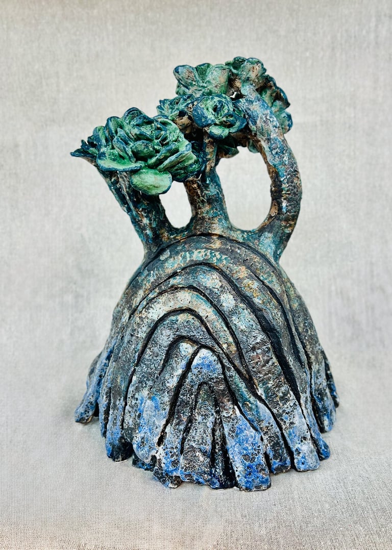 A ceramic plant-like sculpture glazed in green, blue and brown tones