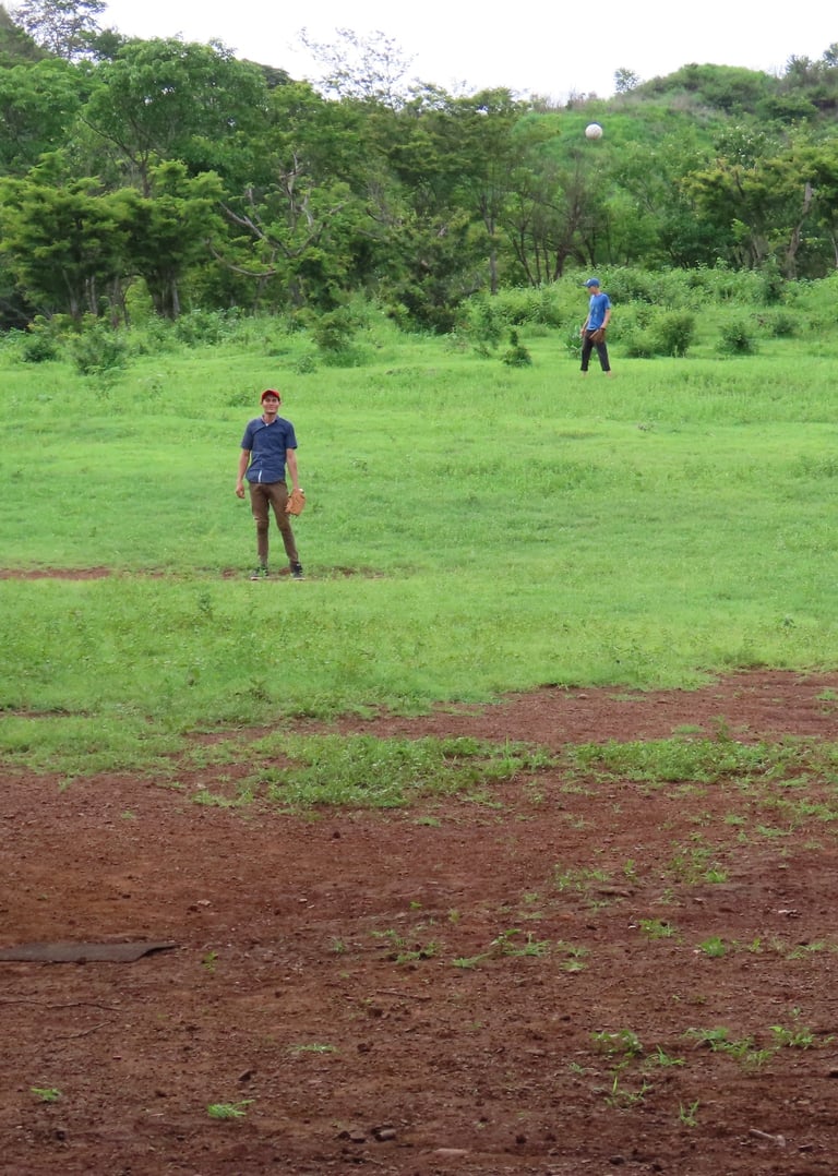 A group of young men playing baseball in a rural countryside.