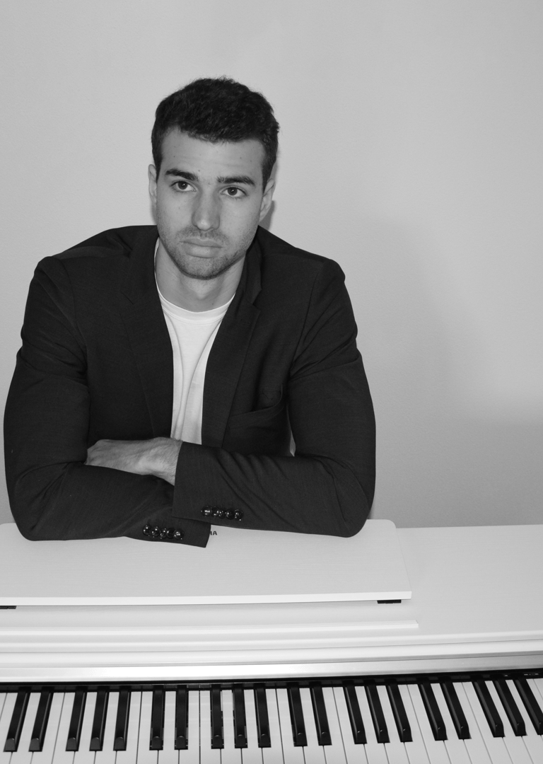 a man in a suit and tie sitting at a piano